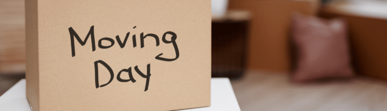 A tan moving box with the words 'Moving Day' written on it, placed on a table.